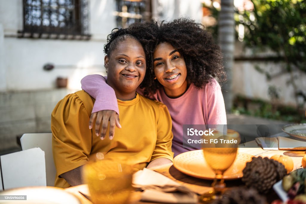 Portrait of sisters embracing at lunch time at home outdoors - including special needs woman Portrait of sisters at home Disability Stock Photo