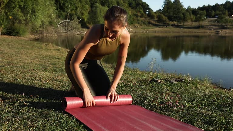 Young woman is packing yoga mat after exercising
