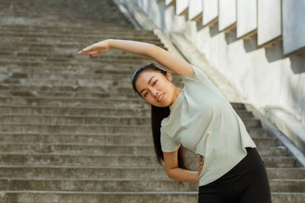 istock Asian sportswoman does side bend training on city street 1345499178