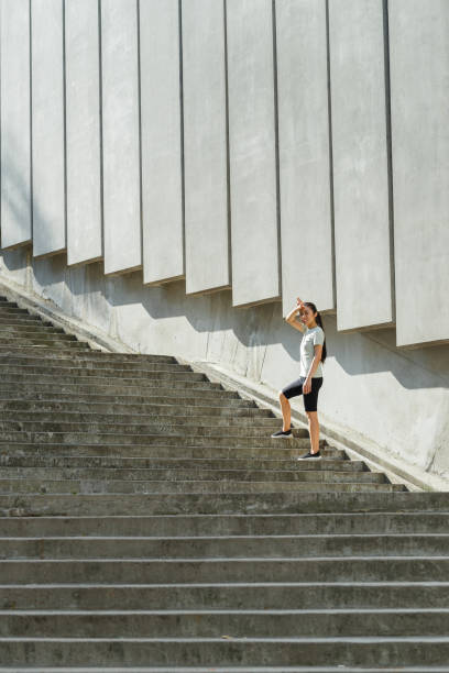 istock Tired Asian woman in tracksuit mops brows on stone steps 1345502700