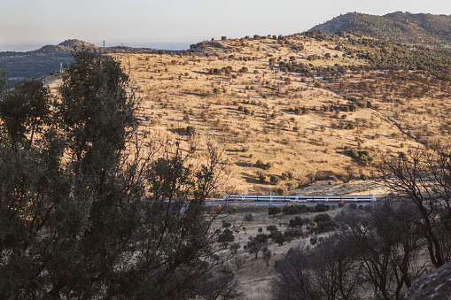 A passenger train traveling through the mountainous landscape northwest of Madrid, Spain