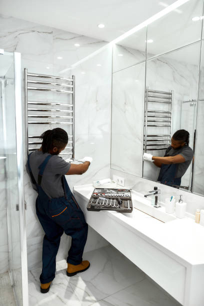 istock Plumber installing new towel rail in light bathroom 1345505786