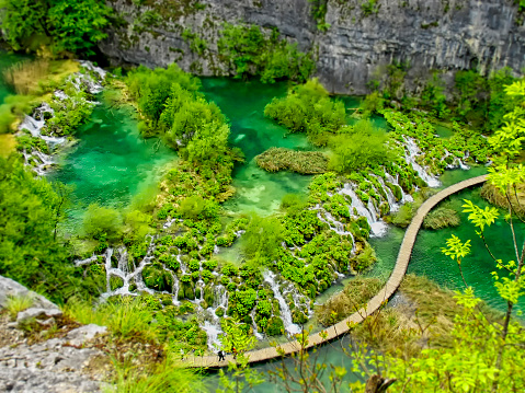 Panoramically view over lakes with cascades and walking trail with tourists at Plitvice Natural Park in Plitvice, Croatia.
