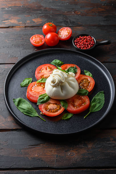 burrata, queijo fresco italiano feito de creme e leite de búfalo ou vaca.  em placa preta velha tábuas de mesa de madeira - buratta - fotografias e filmes do acervo