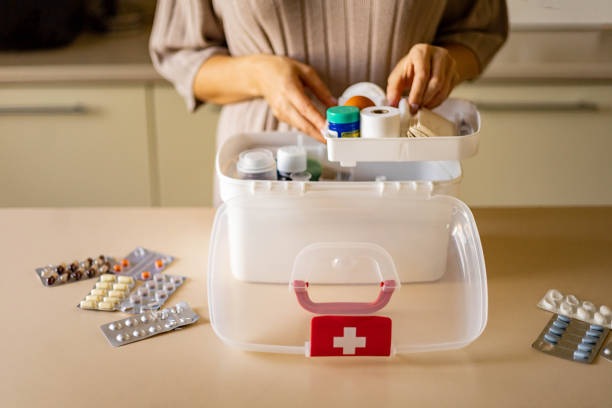 Closeup female hand placing medicament domestic first aid kit. Storage organization emergency supply Closeup female hand neatly placing medicament at domestic first aid kit top view. Storage organization in transparent plastic box drug, pill, syringe, bandage. Fast health help safety emergency supply first aid photos stock pictures, royalty-free photos & images