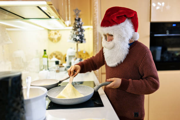 kleiner weihnachtsmann macht weihnachts-crêpes-pfannkuchen in der küche - back somersault stock-fotos und bilder