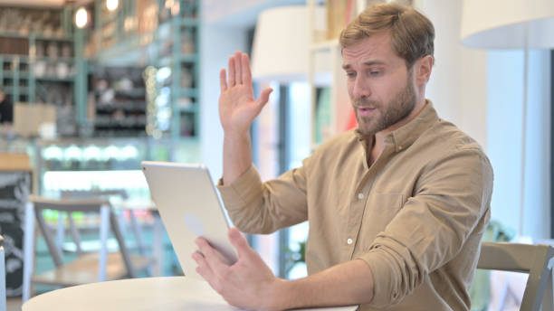 junger mann macht video-chat auf tablet im cafe - 24193 stock-fotos und bilder