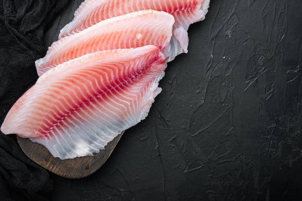istock Raw tilapia fish fillet meat, on black background with copy space for text 1345510488