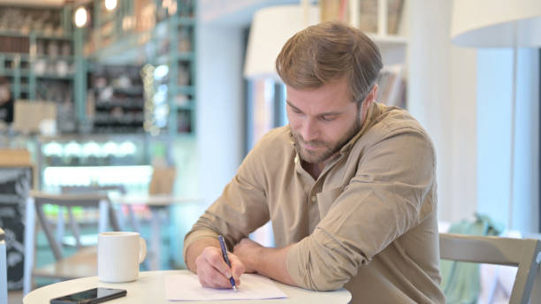 serious young man doing paperwork in cafe - 24201 imagens e fotografias de stock