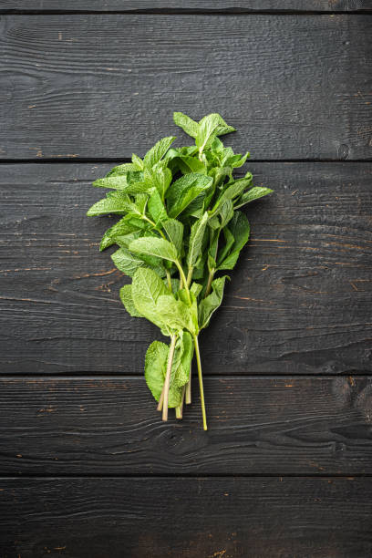 istock Fresh mint leaves herb, on black wooden table background, top view flat lay 1345511652