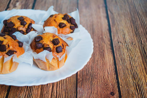 cupcake, with chocolate chips, on white plate, on wooden table, with space for text