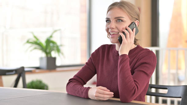istock Young Woman Talking on Smartphone in Office 1345513795