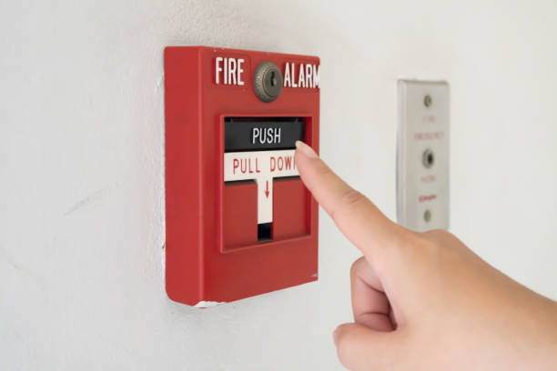 istock Hand of woman reaching to Fire alarm switch system 1345514138