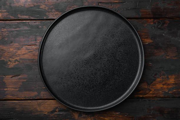 istock Ceramic empty black plate, on old dark  wooden table background 1345515015