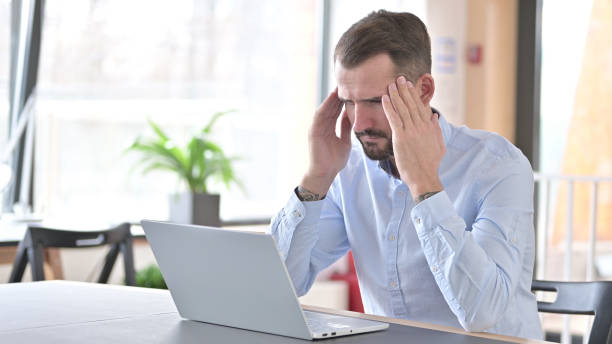 istock Young Man with Laptop having Headache in Office 1345515096
