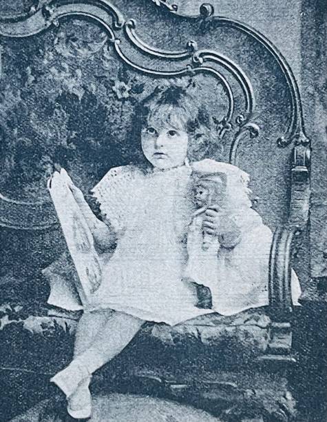 istock Girl sitting on sofa holding a doll and her picture book 1345515132