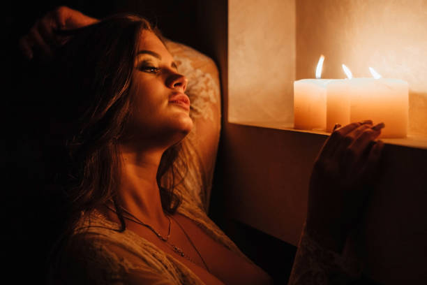 istock Aromatherapy. A sexy brunette in underwear extinguishes candles before bedtime. Romantic setting on Valentine's Day 1345515518