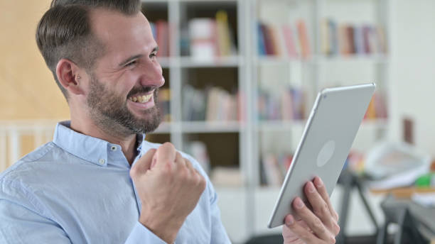 portrait d’un jeune homme célébrant le succès sur tablette - 24424 photos et images de collection