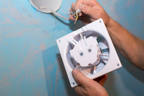 istock Man is installing the wall bathroom fan vent. Restoration process. Wires in hands. Maintenance repair works renovation in the flat. 1345516364