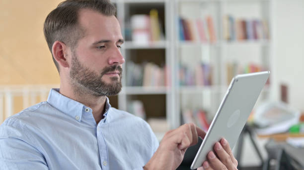 jeune homme concentré utilisant une tablette numérique - 24422 photos et images de collection