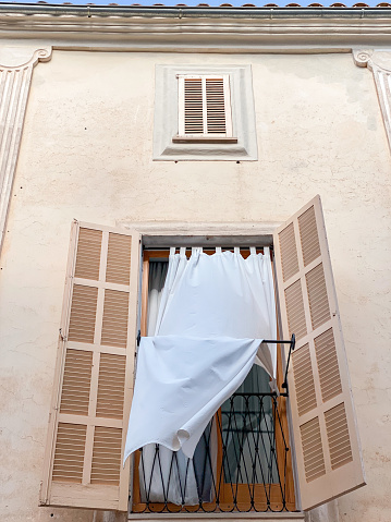 Upward view of an idyllic balcony with a curtain flying in the gentle breeze