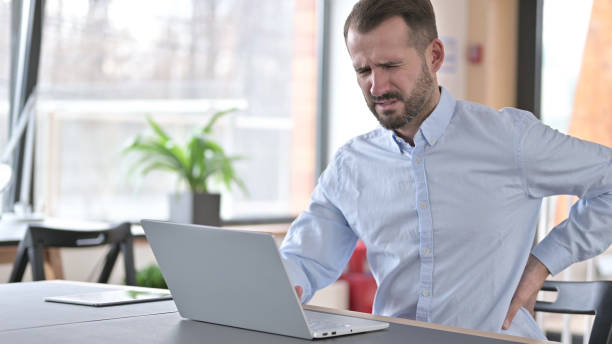 istock Tired Young Man having Back Pain in Office 1345516641