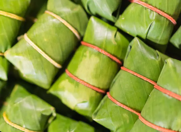 Photo of Khao tom - popular Laotian and Thai Dessert. Steamed Sticky Rice with filling wrapped in banana Leaves. Asian cuisine concept image.