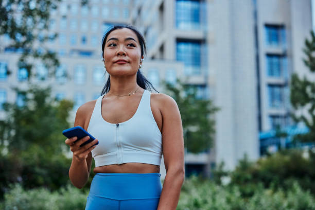 istock Sporty asian woman standing in front after workout and using cellphone 1345518193