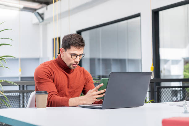 istock Latin man essa in the office for which he works using his mobile phone 1345519290