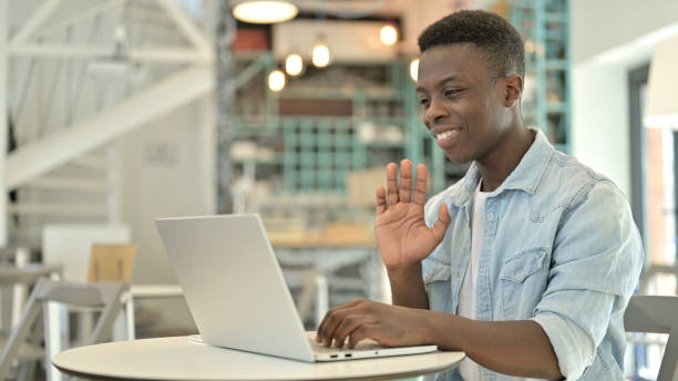 istock Young African Man doing Video Chat on Laptop in Cafe 1345519426