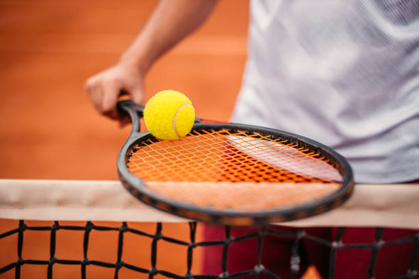 nicht wiederzuerkennbarer mann, der den ball auf dem tennisschläger hält - tennis court tennis ball racket stock-fotos und bilder