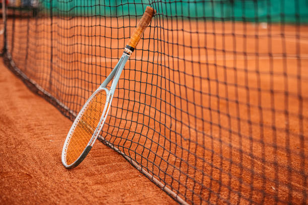 istock Tennis racket leaning on net on court 1345520273