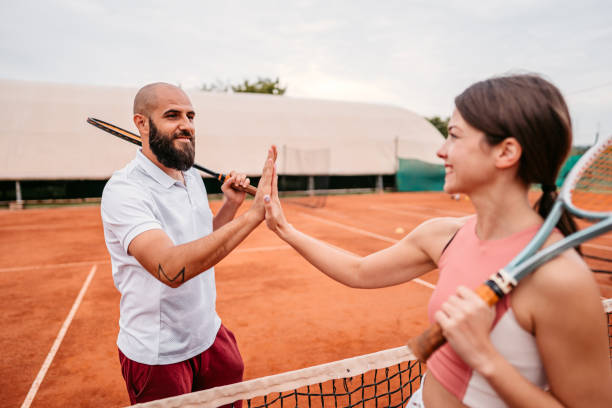 istock Tennis players shaking hands over tennis net 1345520743