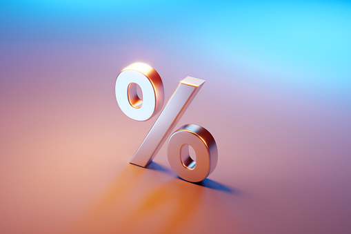 Percentage sign sitting over pink and blue background. Selective focus. Horizontal composition with copy space. High angle view.
