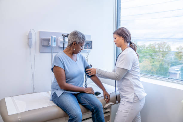 doctor taking senior patients blood pressure - blodtryck orolig bildbanksfoton och bilder