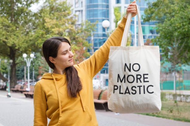 istock A woman shows a fabric reusable bag with the text no more plastic. 1345521812