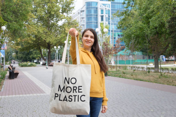 istock A woman shows a fabric reusable bag with the text no more plastic. 1345521836