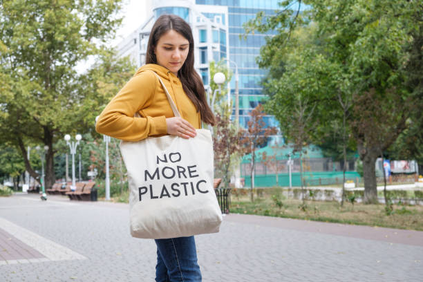 istock A woman shows a fabric reusable bag with the text no more plastic. 1345521837