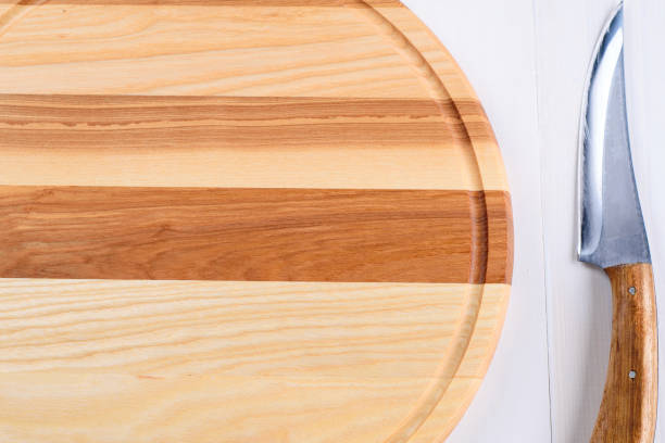 istock Empty circular wooden cutting board for bread, pizza or steak serve and knife on white kitchen table background, copy space. Top view, flat lay 1345522759