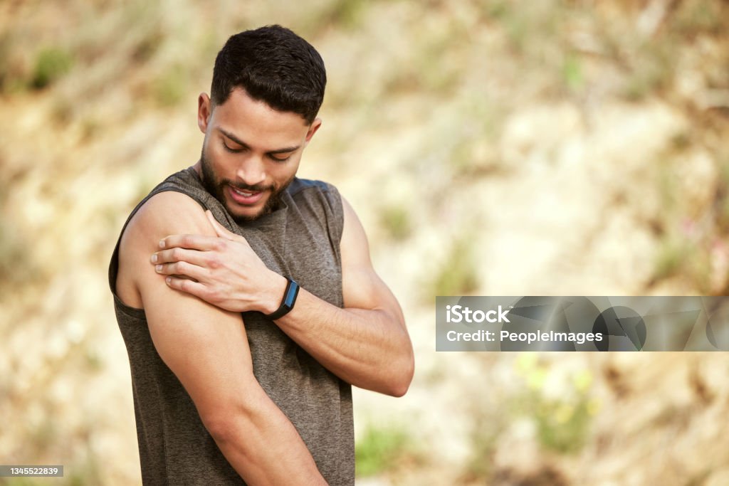 Shot of a sporty young man holding his shoulder in pain while exercising outdoors I might have exerted my muscles too much Muscular Build Stock Photo