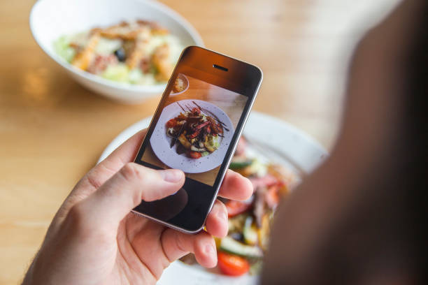 Mężczyzna fotografuje pyszną sałatkę na telefonie w restauracji – zdjęcie