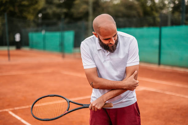 istock Man holding elbow in pain while playing tennis 1345523572
