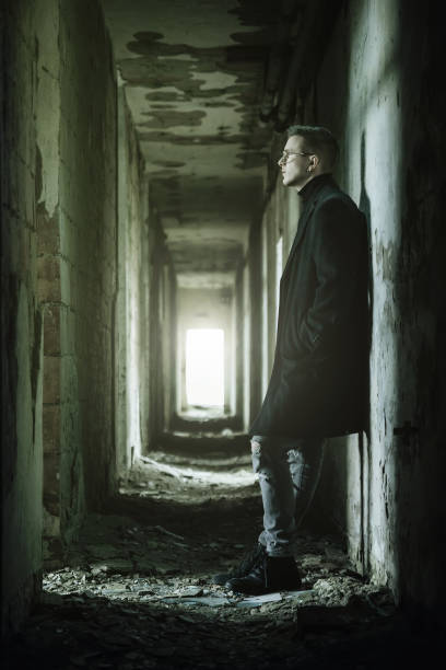 istock Young man with eyeglasses in dark ruined corridor vertical 1345524707