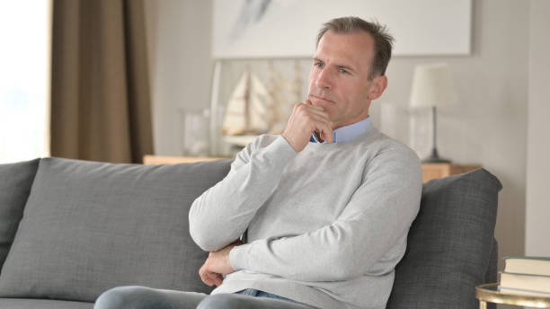 istock Serious Middle Aged  Businessman Sitting on Sofa and Thinking 1345526020