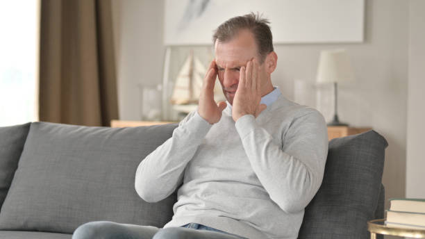 istock Middle Aged Businessman with Headache Sitting on Sofa 1345526045