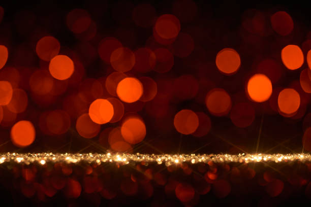 Still life photography of an abstract holiday / party  background. Golden shiny glitter, lens flares, and defocused red lights. Native image size: 7952x5304
