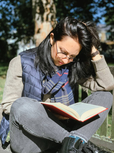 istock Young woman is reading book in park 1345529574