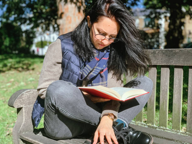 istock Young woman is reading book in park 1345529654