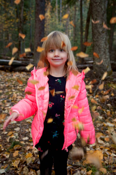 Cute little girl is mesmerized by falling leaves