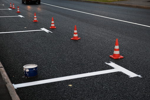 New road markings on asphalt, parking on carriageway along the road. Manual labor, Painting process. Selective focus.